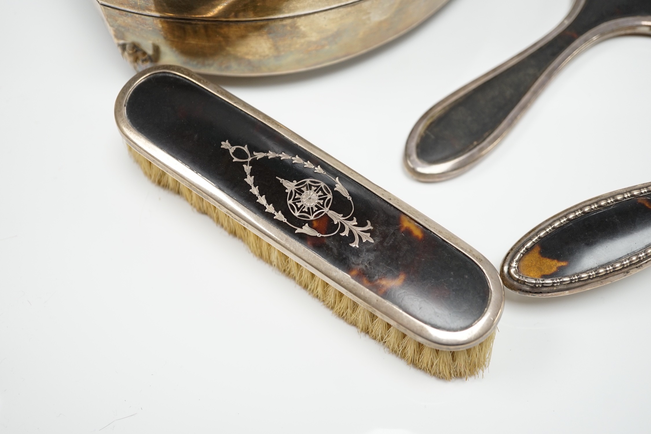 A George V silver and tortoiseshell piqué mounted trinket box, Levi & Salaman, Birmingham, 1918, 19cm and a matched three piece silver and tortoiseshell mounted mirror and brush set.